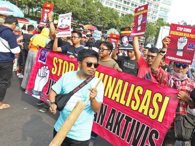 Jurnalis yang tergabung dalam Aliansi Jurnalis Independen (AJI) menggelar aksi jalan mundur saat Car Free Day di Bundaran HI, Jakarta, Minggu (29/9/2019). Kegiatan tersebut bentuk desakan agar Polda Metro Jaya mencabut status tersangka jurnalis Dandhy Dwi Laksono. (Liputan6.com/Herman Zakharia)