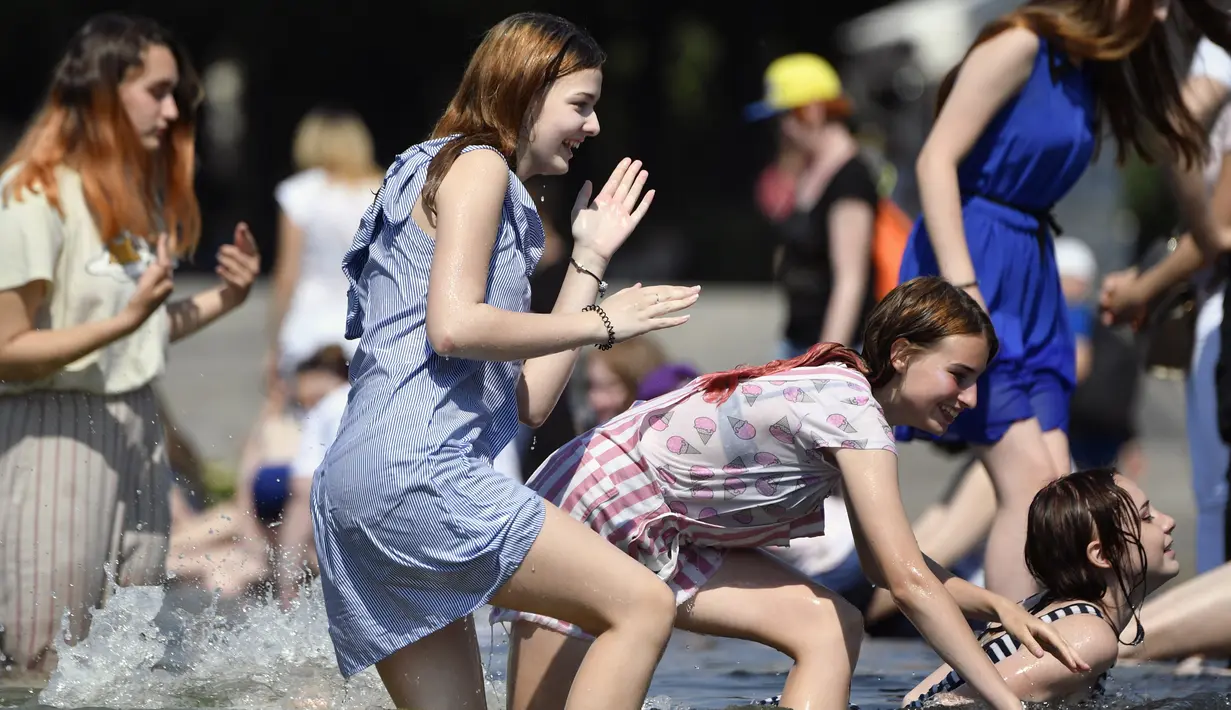 Gadis-gadis Rusia bermain di kolam air mancur di Taman Gorky, Moskow (7/6). Memasuki musim panas, sebagian warga Moskow menghabiskan waktu di taman untuk berjemur atau bermain air di kolam air mancur. (AFP Photo/Alexander Nemenov)