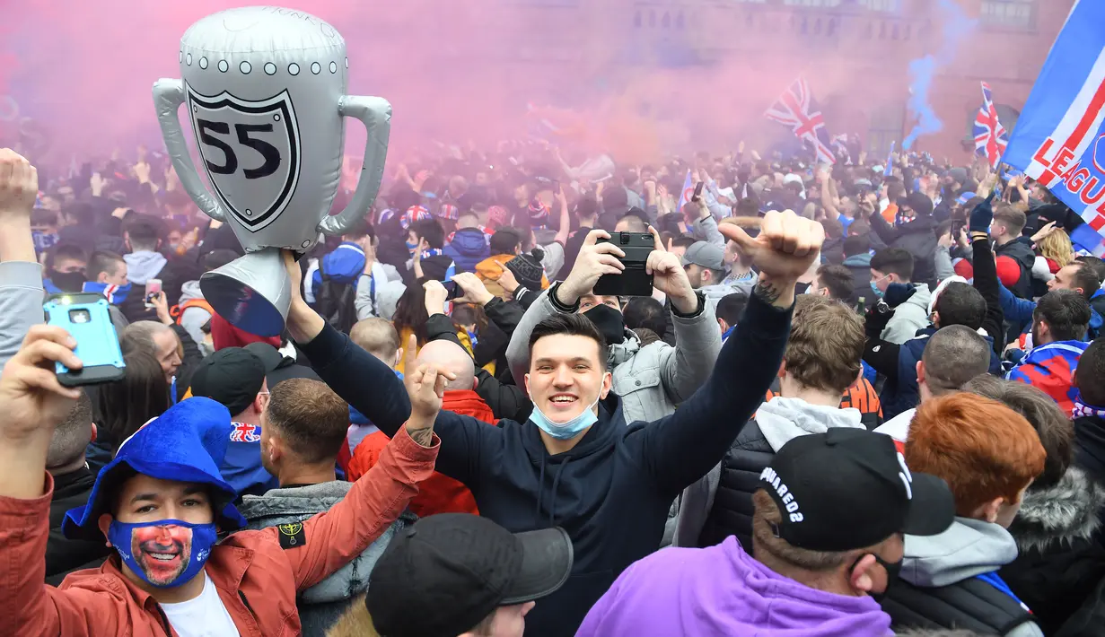 Seorang fans Glasgow Rangers mengangkat balon sebagai replika trofi di luar Ibrox Stadium (7/3/2021) untuk merayakan keberhasilan tim kesayangan mereka merebut gelar Liga Utama Skotlandia setelah memimpin 20 poin dari saingan terdekat, Glasgow Celtic. (AFP/Andy Buchanan)