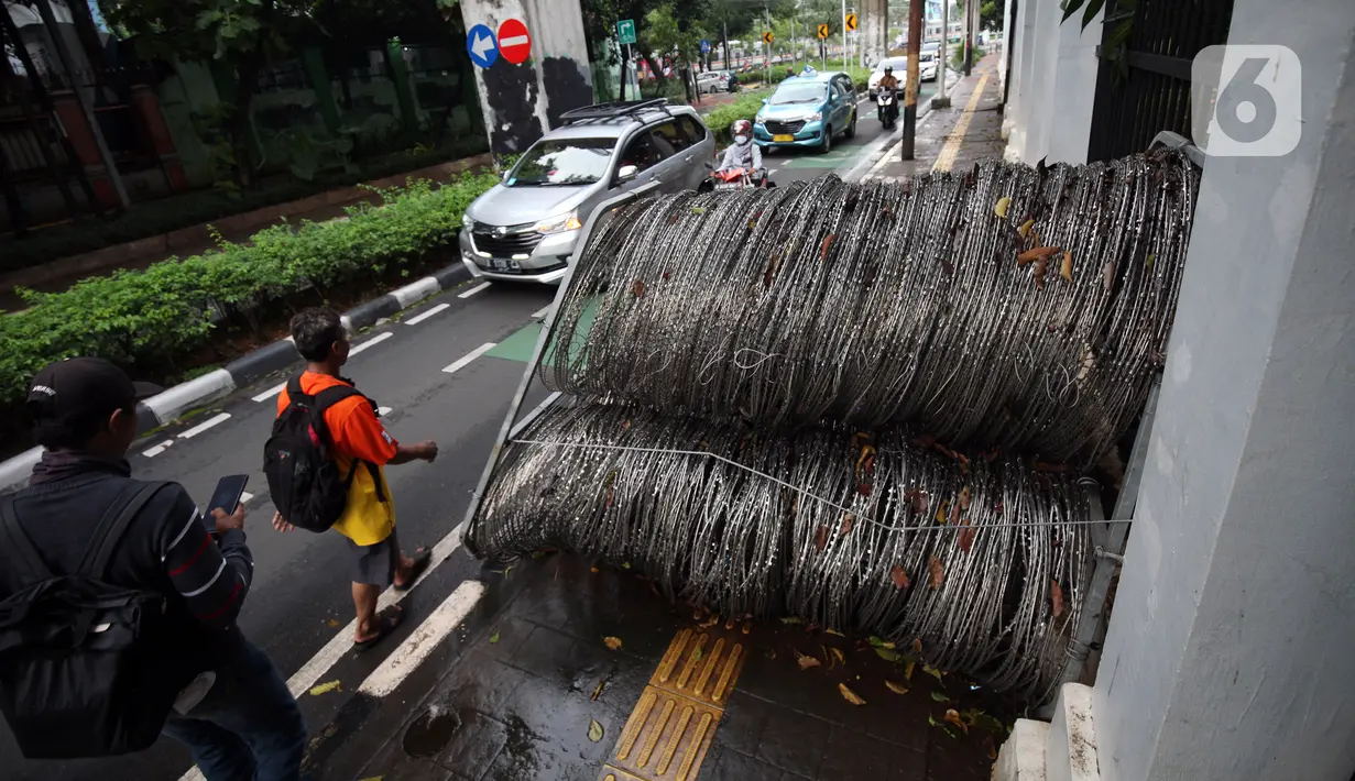 Pejalan kaki berjalan menghindari kawat berduri yang berada di trotoar Jalan Asia Afrika, Jakarta Pusat, Selasa (28/12/2021). Kawat berduri yang berada di trotoar tersebut sangat mengganggu para pejalan kaki yang melintas. (Liputan6.com/Johan Tallo)