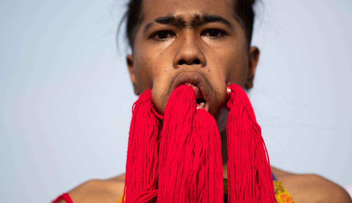 Penganut kuil Loem Hu Thai Su manusukkan benang ke pipinya hingga keluar melalui mulut saat festival vegetarian tahunan di Phuket, Thailand, Jumat (12/10). Setiap peserta harus rela wajahnya ditusuk dengan berbagai benda tajam. (Jewel Samad/AFP)