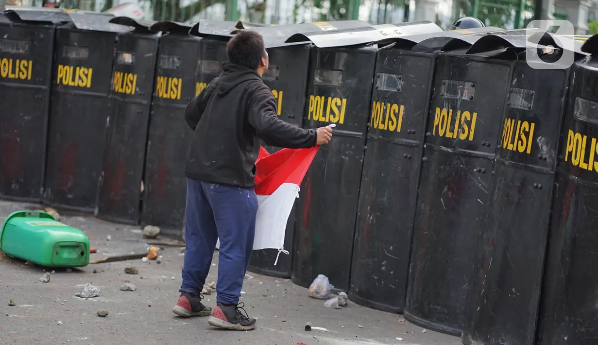 Pengunjuk rasa membawa bendera Merah Putih saat terlibat bentrok dengan polisi di Jalan Medan Merdeka Timur, Jakarta, Kamis (8/10/2020). Bentrokan terjadi akibat massa yang memaksa masuk ke depan Istana Negara untuk berunjuk rasa terkait penolakan UU Cipta Kerja. (Liputan6.com/Immanuel Antonius)