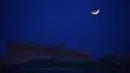 Bulan purnama yang sebagian gerhana terlihat tepat sebelum terbenam di belakang Holocaust Memorial di Montevideo, Uruguay pada Rabu (26/5/2021). (Mariana SUAREZ / AFP)