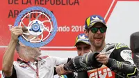 Pembalap LCR Honda, Cal Crutchlow menyemprotkan sampanye pada salah satu krunya saat merayakan kemenangannya pada balapan MotoGP Argentina di atas podium Sirkuit Termas de Rio Hondo, Minggu (8/4). (AP/Natacha Pisarenko)