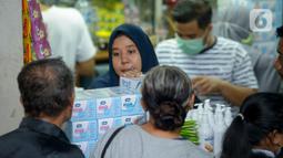 Pedagang melayani pembeli di salah satu toko penjualan masker di Pasar Pramuka, Jakarta Timur, Rabu (4/3/2020). Polda Metro Jaya menggelar sidak di Pasar Pramuka untuk menyikapi lonjakan harga dan kelangkaan masker di pasaran terkait virus corona atau COVID-19. (merdeka.com/Imam Buhori)