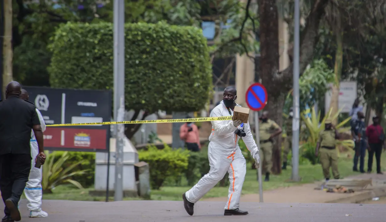 Seorang petugas forensik mengamankan lokasi ledakan di sebelah kantor polisi pusat di Kampala, Uganda (16/11/2021).  Serangan yang terjadi di dekat parlemen Uganda dan markas polisi terjadi hampir bersamaan dengan selisi kurang dari tiga menit. (AP Photo/Nicholas Bamulanzeki)