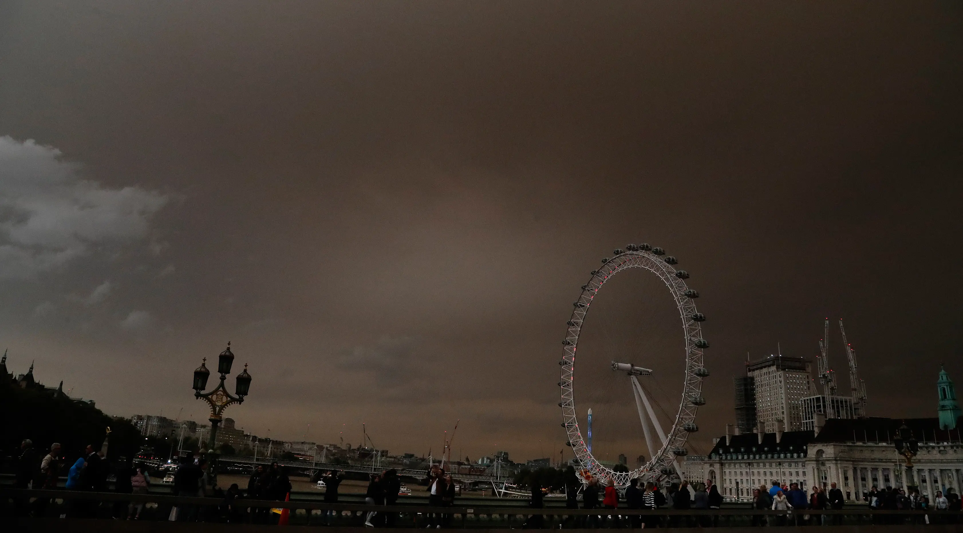 Penampakan langit di atas London Eye yang berwarna kuning kusam menyelimuti kota London, Inggris, Senin (16/10). Fenomena langit yang menjadi mencekam ini disebabkan oleh badai Ophelia yang membawa debu dari Gurun Sahara. (AP Photo/Frank Augstein)