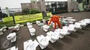 Petugas kebersihan berdiri di antara puluhan jamban yang di letakkan di depan gedung DPR RI, Jakarta, Kamis (3/12). Aksi yang dinamakan “Aksi Djamban DPR” ini menyindir kasus “Papa Minta Saham” yang dilakukan Setya Novanto (Liputan6.com/Immanuel Antonius)