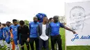 Pemain Timnas Prancis, Patrice Evra, berpose dengan para pemain muda Les Ulis di lapangan latihan Les Ulis di samping poster bergambar dirinya, (23/5/2016). (AFP/Franck Fife)