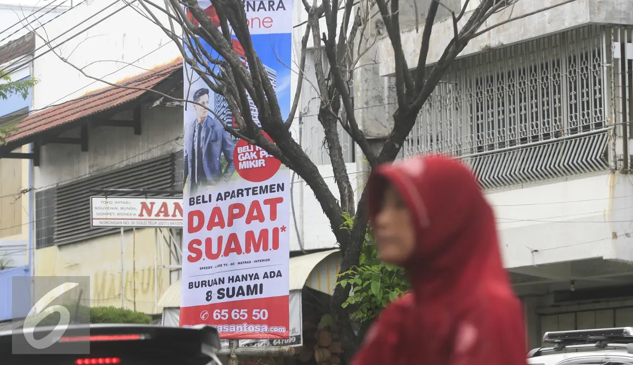 Seorang pengguna jalan melintasi benner ilklan beli apartemen dapat suami di kawasan Nonongan, Solo (3/2/2016). Iklan di pasang untuk menarik minat calon pembeli. (Liputan6.com/Boy Harjanto)