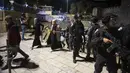 Wanita Palestina melewati barisan polisi Israel saat mereka meninggalkan Gerbang Damaskus ke Kota Tua Yerusalem setelah bentrokan di kompleks Masjid Al-Aqsa (7/6/2021). (AP Photo/Mahmoud Illean)