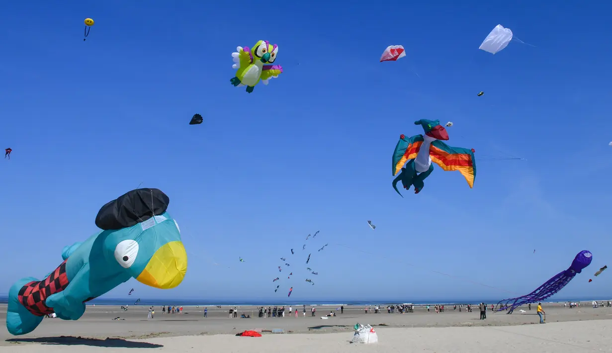 Orang-orang menerbangkan layang-layang berbagai bentuk dan warna dalam Festival Layang-Layang Internasional ke-32 di pantai Berck-sur-Mer, Prancis utara, 18 April 2018. Kegiatan internasional ini berlangsung hingga 22 April 2018. (Denis Charlet/AFP)