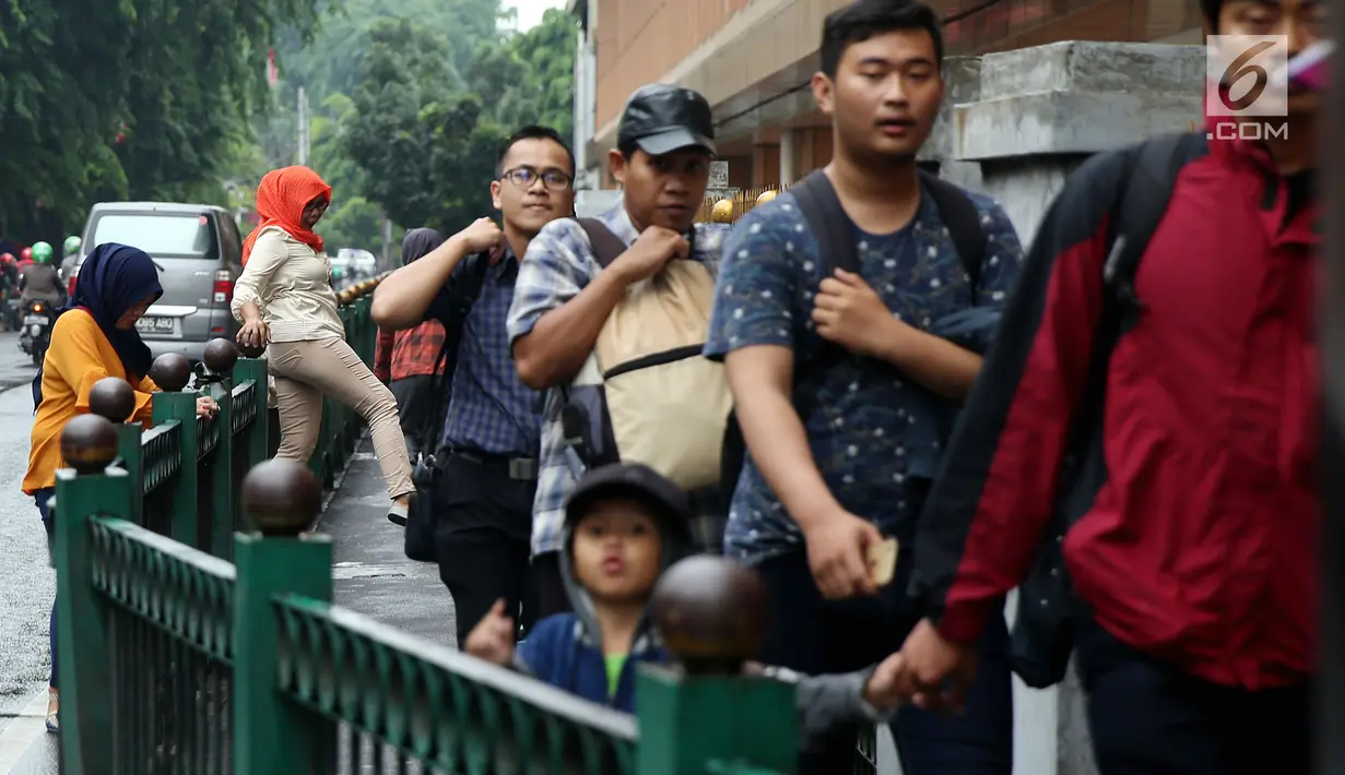 Sejumlah orang berjalan saat beberapa penumpang memanjat pagar pembatas di Stasiun Cikini, Jakarta, Rabu, (20/12). Akses pintu keluar stasiun yang terlalu jauh membuat banyak penumpang mencari jalan pintas dengan melompat pagar. (Liputan6.com/Johan Tallo)