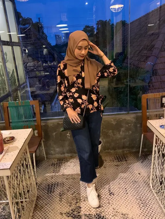 Berprofesi menjadi desainer busana di kota pahlawan. membuat Amira juga memperhatikan style-nya kala pergi keluar rumah. Kini, pilihannya jatuh kepada blouse hitam bermotif bunga, yang dipadu dengan kerudung cokelat dan celana jeans. Ia juga melengkapi penampilannya dengan sepatu kets putih. (Liputan6.com/IG/@amira_krmn)