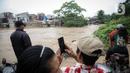 Warga menyaksikan deretan permukiman warga di bantaran Sungai Ciliwung yang terendam banjir, Jakarta, Senin (10/10/2022). Hingga pukul 09.00 WIB hari ini, Badan Penanggulangan Bencana Daerah (BPBD) DKI Jakarta mencatat sebanyak 68 RT di Jakarta terendam banjir akibat luapan Sungai Ciliwung. (Liputan6.com/Faizal Fanani)