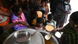 Otoritas sipil mendistribusikan makanan kepada penduduk di tempat penampungan sementara setelah hujan lebat di Chennai, India (8/11/2021). Hujan lebat terus menyebabkan genangan air di Chennai dan daerah sekitarnya. (AFP/Arun Sankar)