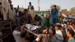 Para warga dan relawan mengangkat tubuh korban yang terluka akibat kecelakaan kereta di Karachi, Pakistan, Kamis (3/11). Menurut petugas, sinyal gagal mengalihkan kereta Zakria Express ke rel lain hingga akhirnya terjadi kecelakaan. (AP Photo/Shakil Adil)