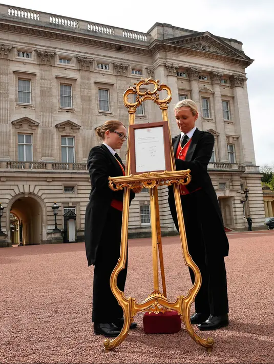 Senior footman Olivia Smith dan footman Heather McDonald saat memajang pengumuman kelahiran bayi baru kerajaan di halaman depan Istana Buckingham, London, Inggris, Senin (23/4). Kate Middleton melahirkan di RS St. Mary. (Pool Photo via AP)