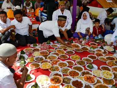 Orang-orang menikmati makan siang selama perayaan maulid akbar Nabi Muhammad SAW di Banda Aceh, Aceh, Kamis (6/2/2020). Acara maulid akbar tersebut menyediakan 808 hidangan dari 90 desa dan instansi pemerintah dengan mengundang 25.000 tamu dari berbagai daerah. (Photo by Chaideer MAHYUDDIN / AFP)