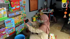 Perajin memfoto hasil dari bahan daur ulang untuk dipasarkan secara online di Kaleng Lani  di kawasan Tanah Baru, Depok, Jawa Barat, Rabu (9/3/2022). Beragam kerajinan tangan seperti celengan, tempat pensil, tempat sampah, dan lain-lain terbuat dari kayu dan kaleng bekas. (merdeka.com/Arie Basuki)