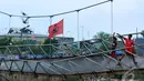 Para bocah ini bermain di Jembatan gantung yang menghubungkan Duri Pulo dan Grogol, Petamburan, Jakarta Barat. Meski rusak mereka tetap asyik bermain burung dara (Liputan6.com/Andrian M Tunay).