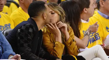 Penyanyi, John Legend bersama sang istri Chrissy Teigan terlihat berciuman saat menonton pertandingan final NBA 2016 antara Golden State Warriors dan Cleveland Cavaliers di Oracle Arena, California, USA (2/6/2016). (Kyle Terada-USA TODAY Sports)