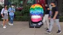 Orang-orang melewati tengkorak yang dihias selama pameran edisi keempat "Mexicraneos" (Mexisculls) di Reforma Avenue, Mexico City pada 23 Oktober 2020. Instalasi sebanyak 55 tengkorak berbagai warna tersebut menghiasi jalanan sebagai bagian dari perayaan Day of the Dead. (ALFREDO ESTRELLA/AFP)