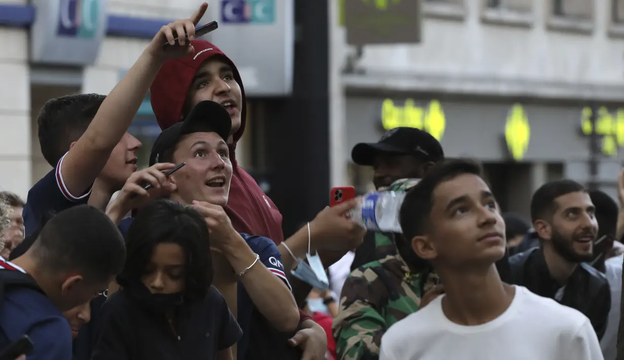 Reaksi para fans ketika bintang sepak bola Argentina, Lionel Messi muncul dari balkon hotelnya di Paris, Selasa (10/8/2021). Di Paris Saint-Germain (PSG), Messi akan dikontrak selama 2 tahun dan menerima gaji €35 juta per musim. (AP Photo/Adrienne Surprenant)