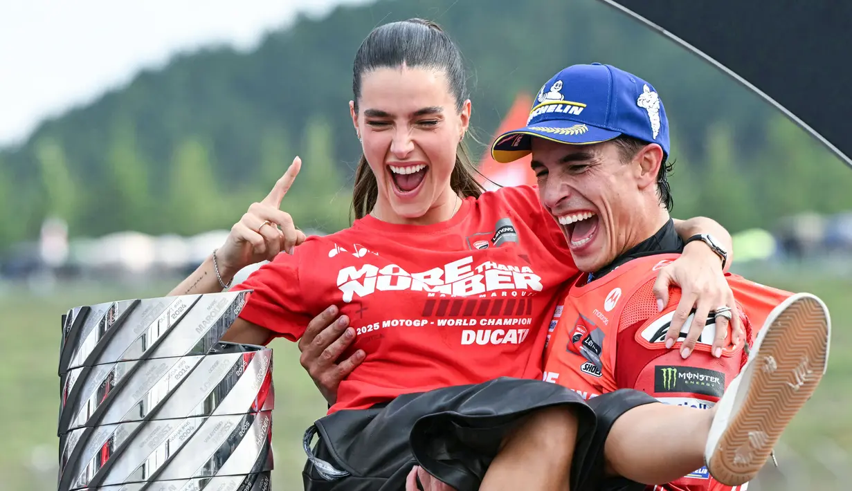 Pembalap Ducati Lenovo, Marc Marquez, bersama kekasihnya, Gemma Pinto, merayakan keberhasilan menjuarai MotoGP 2025 di Sirkuit Motegi, Jepang, Minggu (28/09/2025). (AFP/Toshifumi Kitamura)