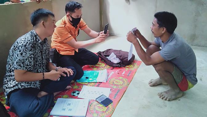 Dua orang petugas PT Pos Indonesia saat memproses pencarian bantuan sosial tunai (BST) untuk kelompok orang rimba Jambi di Dusun 24, Kabupaten Batanghari, Jambi, Jumat (17/7/2020). Bantuan tersebut untuk masyarakat kurang mampu terdampak Covid-19. (Liputan6.com/Gresi Plasmanto)