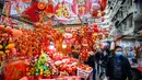 Pejalan kaki berjalan melewati kios yang menjual dekorasi di Hong Kong (14/1/2021). Menjelang Tahun Baru Imlek, tahun ini menandai Tahun Sapi, yang jatuh pada 12 Februari. (AFP/Anthony Wallace)