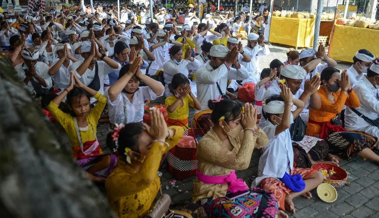 Umat Hindu yang mengenakan pakaian tradisional berdoa pada perayaan Hari Raya Kuningan di Pura Sakenan, Pulau Serangan, Denpasar, Bali, Sabtu (20/11/2021). Kuningan merupakan hari terakhir perayaan Galungan yang diyakini sebagai hari naiknya roh suci leluhur kembali ke surga. (Sonny TUMBELAKA/AFP)