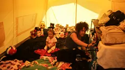 Samir Gonzalez duduk bersama putrinya di dalam tenda mereka di sebuah kamp bagi para migran Venezuela yang tunawisma, di Bogota, Kolombia (21/11). Kamp tersebut dibangun oleh sekretaris kesejahteraan sosial kota. (AP Photo/Ivan Valencia)