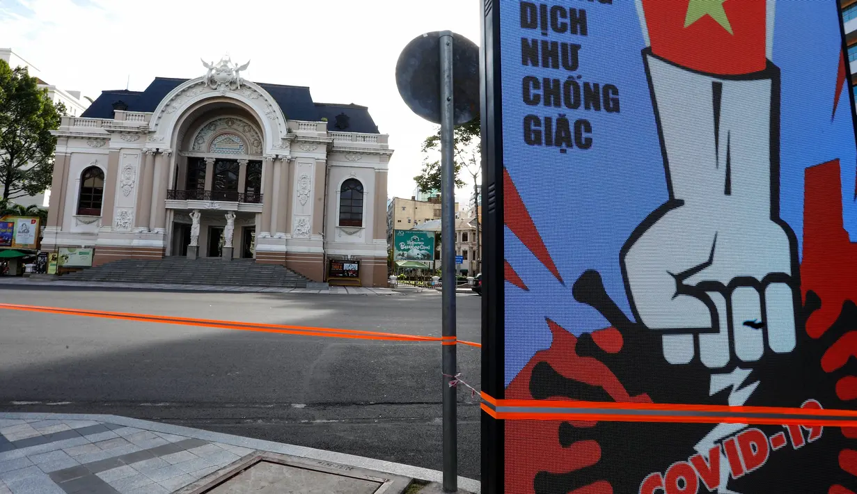 Layar elektronik menampilkan pesan yang berkaitan dengan perang melawan Covid-19 dengan latar belakang gedung Opera Saigon pada hari pertama pemberlakuan lockdown di Kota Ho Chi Minh, Vietnam, Jumat (9/7/2021). (AFP/Huu Khoa)