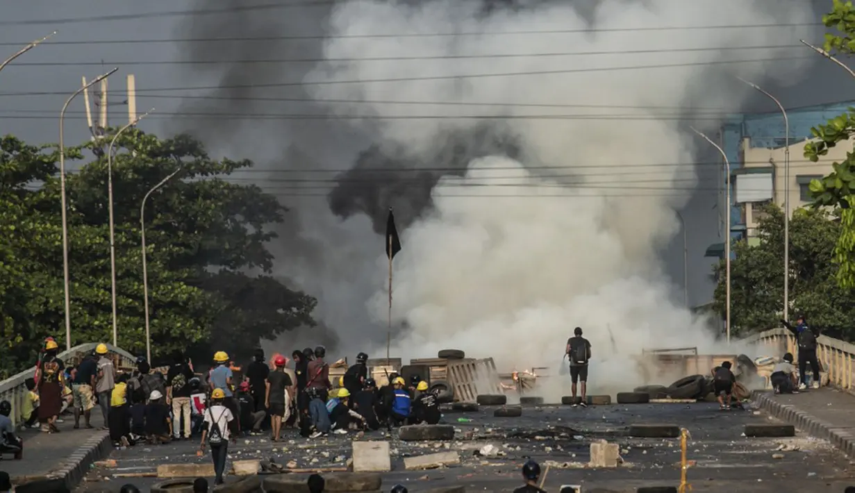 Para pengunjuk rasa berlindung di balik perisai buatan sendiri saat mereka menghadapi polisi selama tindakan keras terhadap demonstrasi menentang kudeta militer di Yangon, Myanmar, 16 Maret 2021. (STR/AFP)