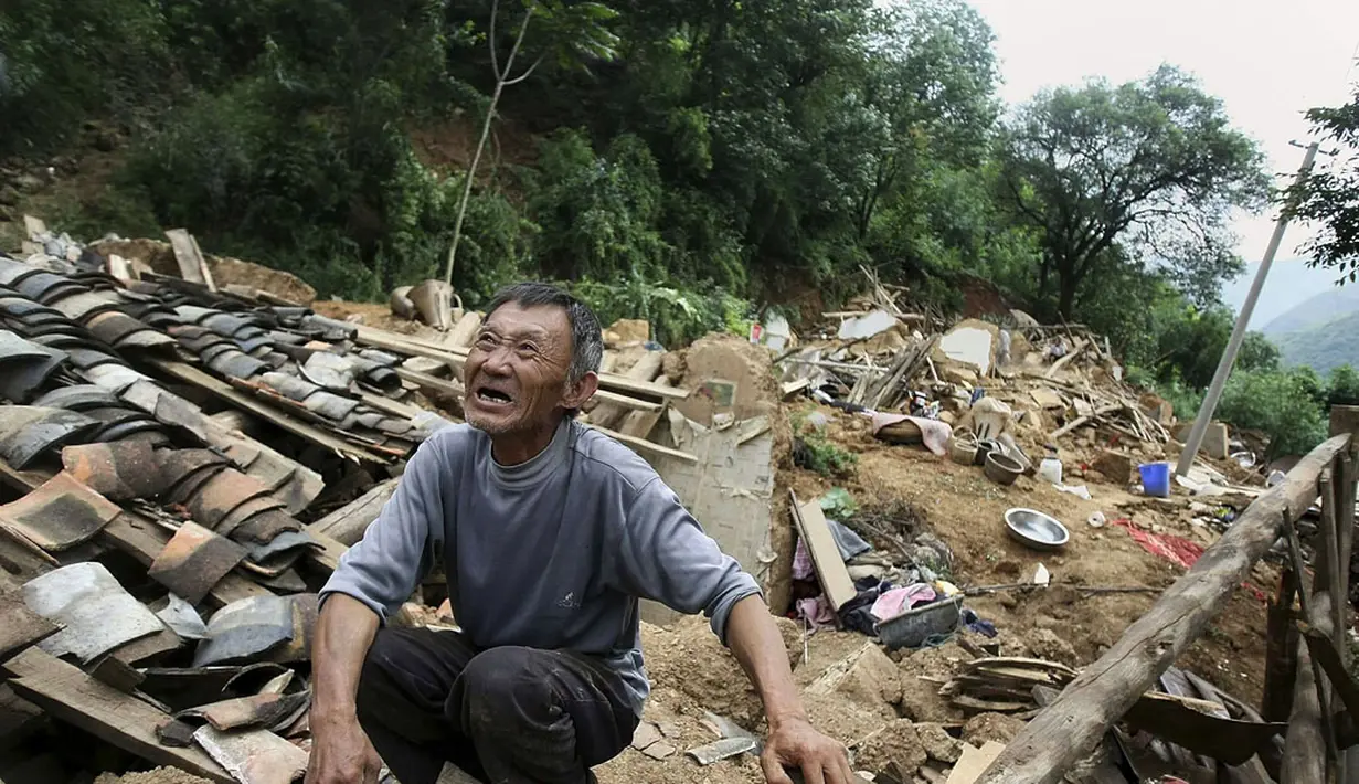 Salah satu korban menangis di atas puing-puing rumahnya yang rusak akibat gempa di Longtoushan, provinsi Yunan, Tiongkok, (6/8/2014). (REUTERS/Stringer)