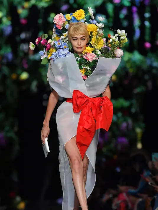 Top model Gigi Hadid mengenakan rancangan rumah mode Moschino saat Milan Fashion Week di Italia, Kamis (21/9). Dalam catwalknya Gigi Hadid mengenakan atribut penuh bunga di tubuhnya. (AFP Photo/Marco Bertorello)