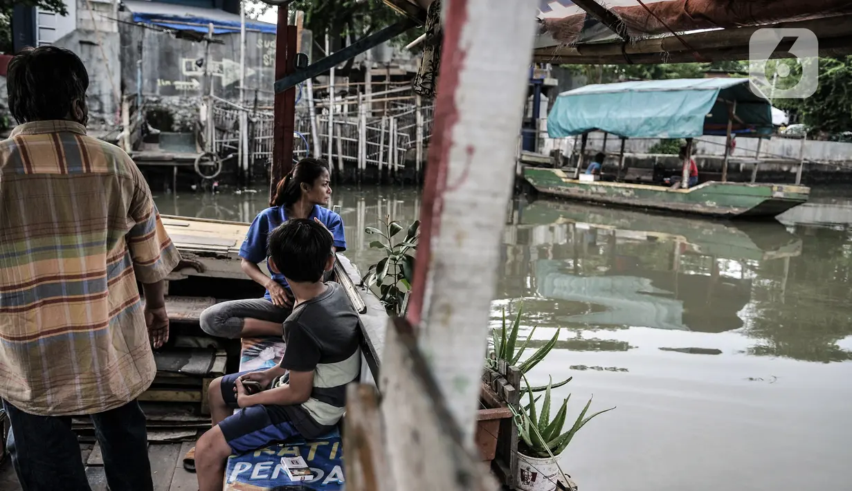 Warga menaiki perahu eretan saat menyeberangi Kali Sunter, Rawa Badak, Jakarta, Rabu (20/1/2021). Sejak pandemi COVID-19, pendapatan Hendi dan penarik perahu eretan lainnya menurun akibat anak sekolah menerapkan pembelajaran dari rumah. (merdeka.com/Iqbal S. Nugroho)