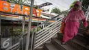 Warga menuruni tangga Jembatan Penyeberangan Orang di Tanjung Barat, Jakarta, Jumat (11/11). Buruknya desain menyebabkan JPO tersebut tidak tersambung, sehingga warga harus membeli tiket kereta jika ingin menyeberang. (Liputan6.com/Immanuel Antonius)