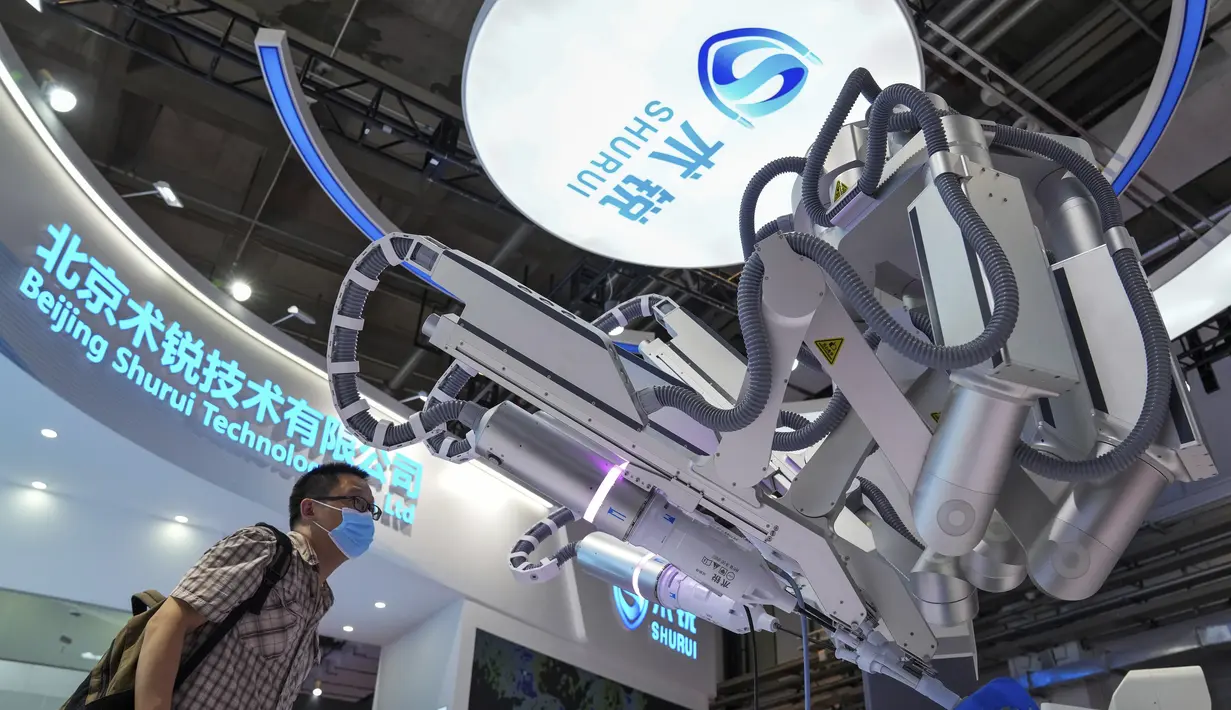 Seorang pengunjung yang mengenakan masker melihat lebih dekat lengan robot buatan China yang digunakan untuk ahli bedah selama Konferensi Robot Dunia di Pusat Konferensi dan Pameran Internasional Yichuang di Beijing, Kamis (18/8/2022). (AP Photo/Andy Wong)