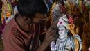 Seorang seniman India memberikan sentuhan terakhir untuk menyelesaikan pembuatan dewa Hindu Rama di sebuah lokakarya di Hyderabad, India (15/3). Para seniman ini membuat patung dewa menjelang festival Rama Navami. (AFP/Noah Seelam)