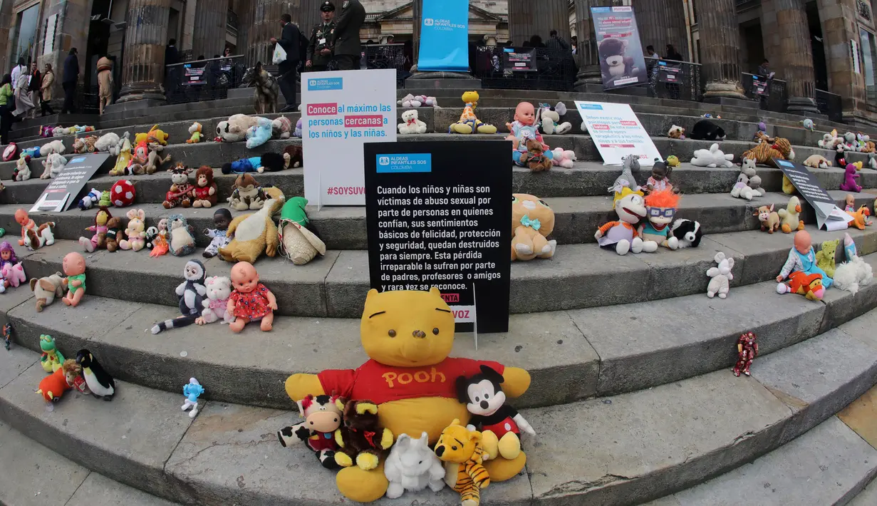 Boneka mainan diletakkan di halaman gedung Kongres Kolombia untuk memprotes kekerasan seksual terhadap anak-anak di Bogota, Selasa (20/11). Protes bertujuan untuk meningkatkan kesadaran tentang tanggung jawab perlindungan anak-anak. (DANIEL MUNOZ/AFP)