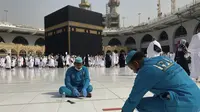 Pekerja menghapus tanda-tanda jarak sosial di Masjidil Haram di kota suci Muslim Mekkah, Arab Saudi, Minggu (6/3/2022). Arab Saudi mengambil kebijakan untuk mengakhiri semua pembatasan Covid-19 termasuk kebijakan jaga jarak dan menggunakan masker di luar ruangan. (AP Photo/Amr Nabil)