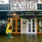 Aimee Cutter, pemilik restoran Beach House, berjalan menembus banjir kiriman dari Danau Pontchartrain di Lakeshore Drive, Mandeville, La., akibat dampak Badai Tropis Barry, Sabtu, 13 Juli 2019. (Matthew Hinton/AP)