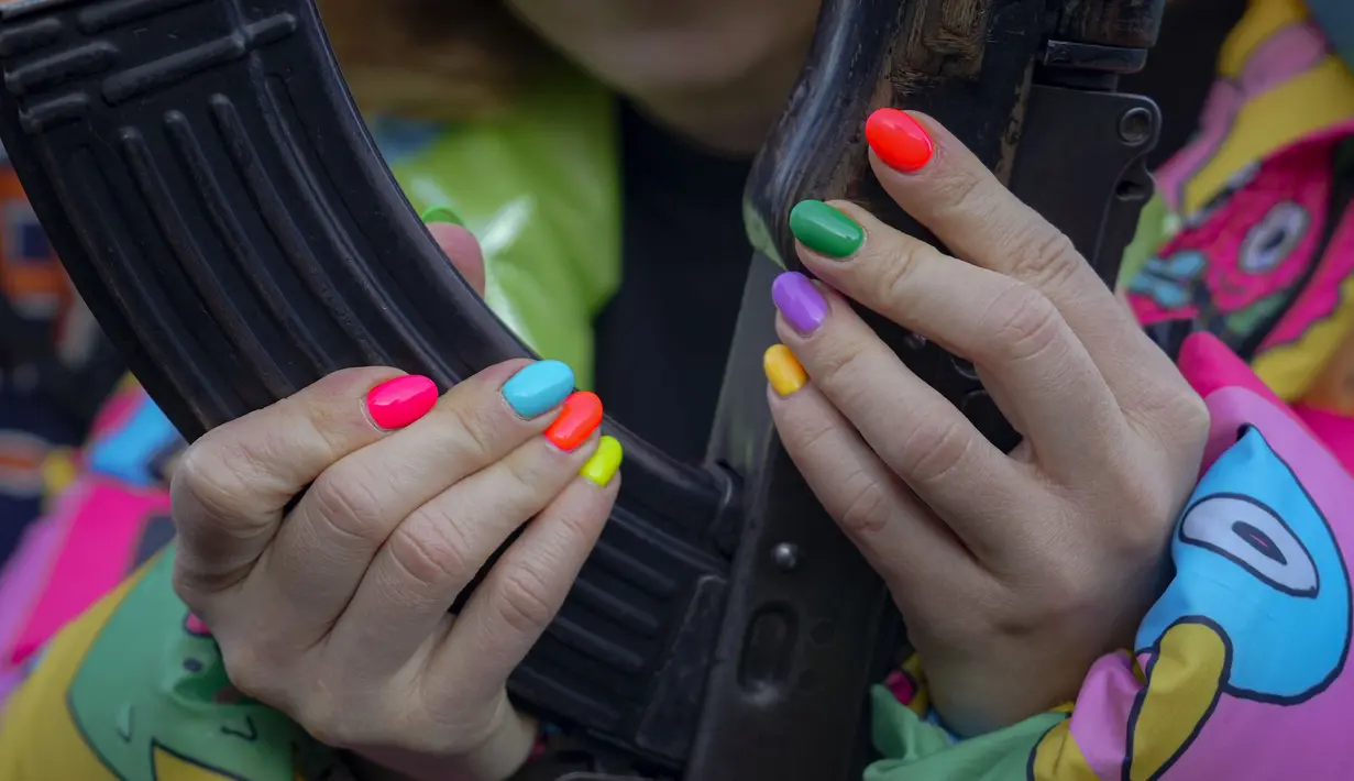 Seorang wanita memegang senjata selama pelatihan perang dasar untuk warga sipil oleh Unit Pasukan Khusus Azov, dari Garda Nasional Ukraina, di Mariupol, wilayah Donetsk, Minggu (13/2/2022). Mereka disiapkan untuk bisa bertahan di tengah kekhawatiran akan invasi Rusia. (AP Photo/Vadim Ghirda)
