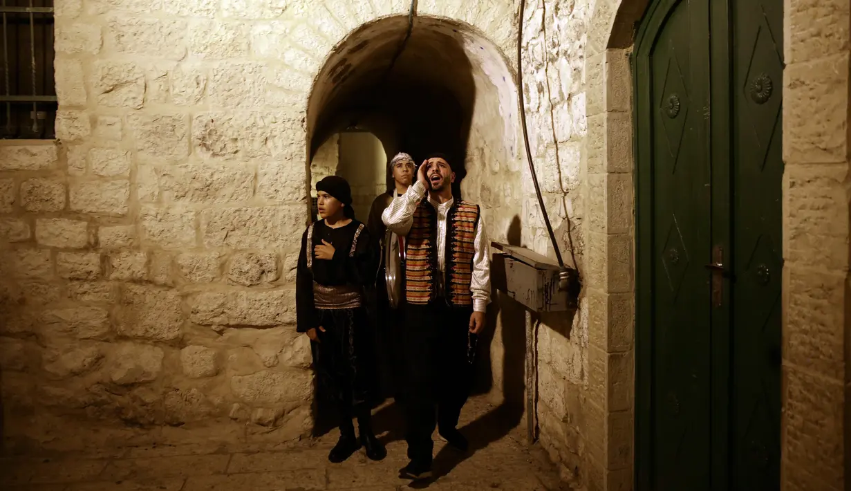 Kelompok pemuda Palestina berpakaian tradisional berteriak membangunkan kaum muslim untuk sahur di Kota Tua Yerusalem, Selasa (5/6). Mereka menyusuri jalan-jalan kota, masuk ke gang-gang kecil di sudut-sudut permukiman warga. (AP/Mahmoud Illean)