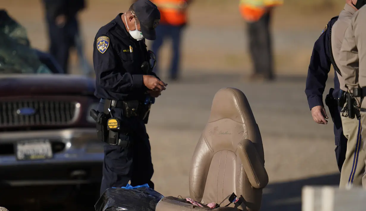 Petugas memilah bukti dan puing-puing di lokasi kecelakaan mematikan truk yang menabrak mobil SUV di Holtville, California (2/3/2021).  Menurut Komandan Polisi Lalu Lintas Jalan Tol Perbatasan, Omar Watson. sepuluh orang tewas di antaranya berkewarganegaraan Meksiko. (AP Photo/Gregory Bull)