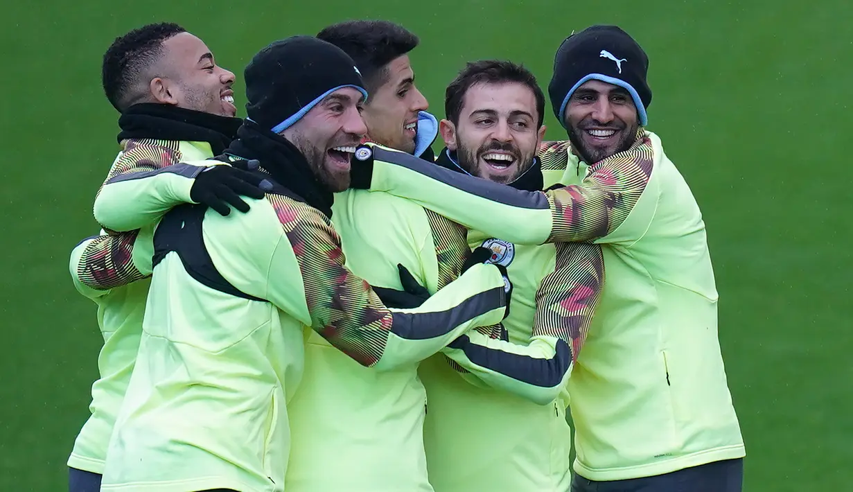 Para pemain Manchester City bercanda selama melakukan pemanasan selama sesi pelatihan tim di City Football Academy di Manchester, Inggris barat laut (25/2/2020). City akan bertanding melawan Real Madrid pada leg pertama babak 16 Liga Champions di Bernabeu. (AFP Photo/Jon Super)