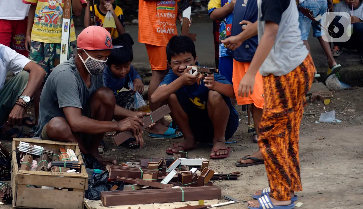 Anak-anak mengamati orang dewasa membuat senjata tembakan dari triplek bekas untuk mereka mengusir kejenuhan usai belajar secara online di Parakan, Tangerang Selatan, Jumat (27/11/2020). Hampir 10 bulan mereka tidak melakukan aktivitas belajar tatap muka karena Covid 19. (merdeka.com/Dwi Narwoko)