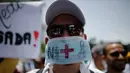 Seorang dokter memakai masker saat unjuk rasa menuntut Presiden Venezuela Nicolas Maduro karena memburuknya ekonomi dan kondisi kemanusiaan di Caracas, Venezuela, (22/5). Sedikitnya 46 orang telah meninggal dunia. (AP Photo/Ariana Cubillos)